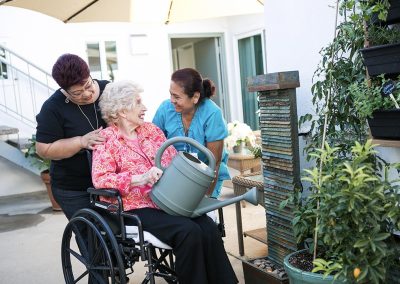 Caregivers with guest watering the plants